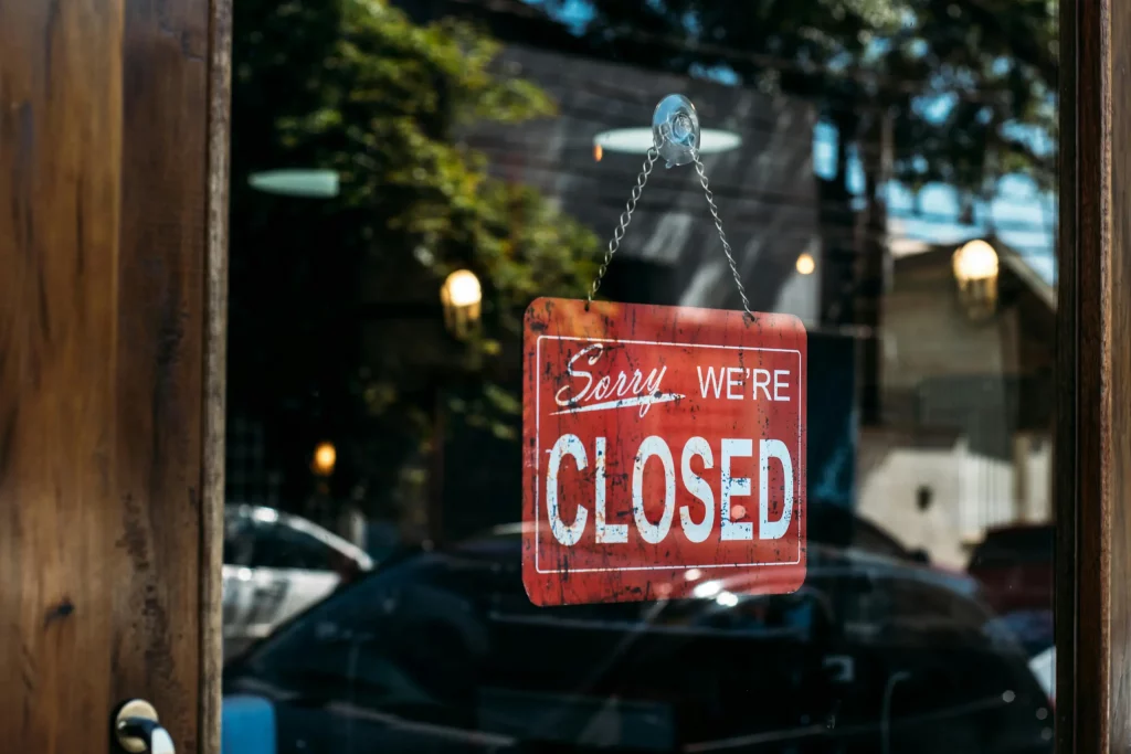 Rotes Schild mit der Aufschrift ‚Sorry we’re closed‘ hängt an einer Glastür. Symbolfoto für Laden geschlossen, Betriebsruhe oder Geschäftspause.